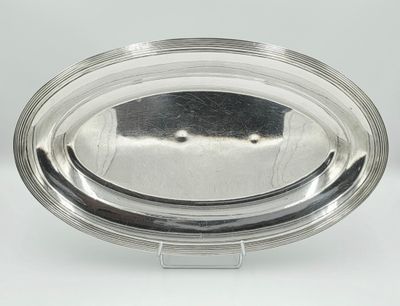 an oval silver plate on a stand with a clear glass lid