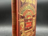 an old book with a red cover sitting on top of a table