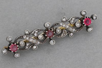 un gros plan d'une broche en argent et en or sertie de pierres roses