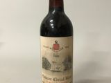 an old bottle of red wine sitting on a white surface