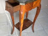 une petite table en bois avec un plateau en marbre, posée sur un sol carrelé
