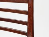 the back of a wooden chair against a white wall
