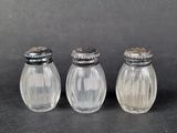 three glass salt and pepper shakers sitting on a black surface