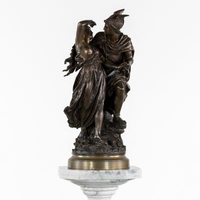 une statue en bronze représentant une femme tenant un enfant dans ses bras, posée sur un socle en marbre