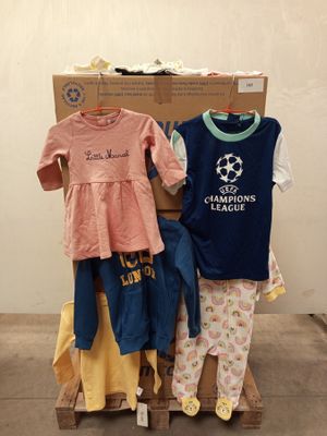 une pile de vêtements pour bébés posée sur une palette devant un carton