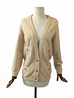 cardigan beige à mailles torsadées sur un mannequin de boutique