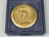 gold medal in a blue box on a white surface
