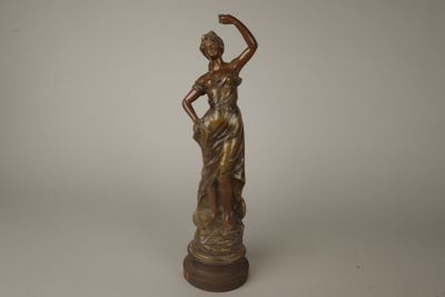 une statue en bronze représentant une femme tenant une balle dans la main