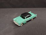 a green toy car with a black top on a black surface
