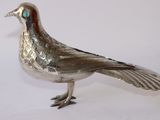 a silver bird that is standing on a white surface