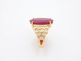 a close up of a gold ring with a red stone and diamonds
