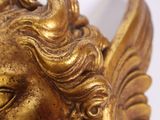 a gold statue of a winged head on a white background