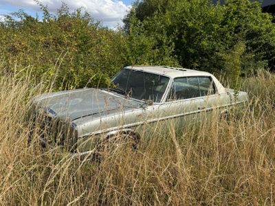 une vieille voiture abandonnée dans les hautes herbes