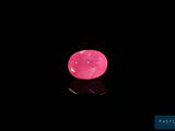 un diamant rose sur une surface noire, avec un reflet