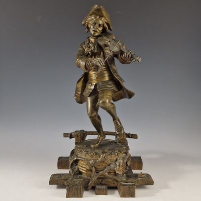 une statue antique en bronze représentant un homme jouant du violon