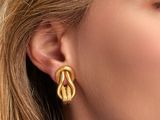 a close up of a woman wearing a pair of gold earrings