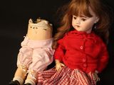 two dolls sitting next to each other on a black background