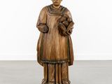 a wooden statue of a man holding a book in his hands