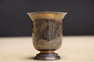 un vase en argent posé sur une table, sur fond noir