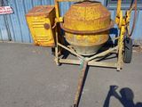 a cement mixer sitting on a cart in front of a building