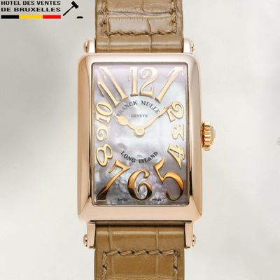 a gold watch with a brown leather strap on a white background