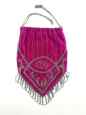 sac à main en velours rose orné de perles argentées et de franges sur fond blanc