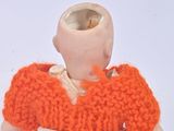 an orange knitted doll that is holding a cell phone