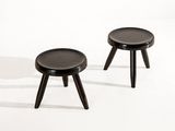 deux petits tabourets noirs posés sur une surface blanche