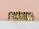 a close up of a gold bracelet on a marble surface