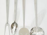 quatre cuillères et une spatule posées sur un plan de travail blanc