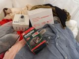 a pile of clothes and a box on a bed