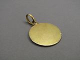 a close up of a gold plated pendant on a gray surface