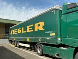 un semi-remorque vert garé sur un parking