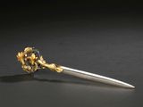 a silver and gold flower on top of a knife