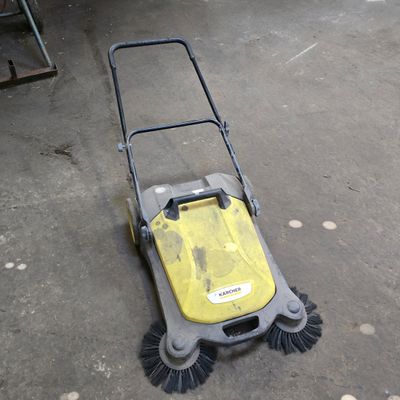 yellow and black push mower laying on the ground in a garage