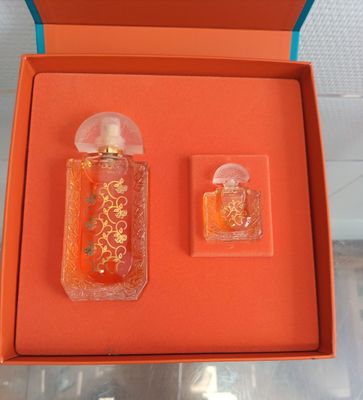une boîte orange contenant deux flacons de parfum et un petit flacon de parfum
