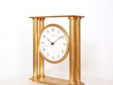 une horloge en or posée sur une table blanche