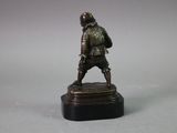 bronze figurine of a man with a backpack on his back