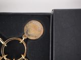 a gold keychain with a coin on it in a black box