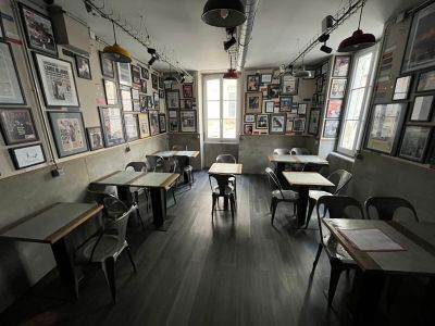 de nombreuses tables et chaises dans une pièce où sont accrochés des tableaux aux murs