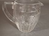 a clear glass pitcher with a handle on a table