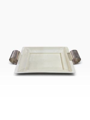 a white plate with a metal handle on a white surface