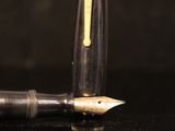 a close up of a fountain pen with a reflection on a black surface