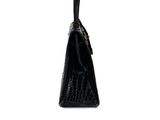 a black handbag with a gold handle on a white background
