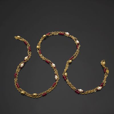 un collier en or orné de perles et de grenats sur fond noir