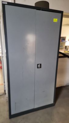 une armoire métallique dans un garage, avec un autocollant jaune sur la porte