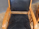 a black leather chair with a wooden frame on a wooden floor