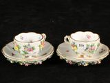 two cups and saucers with floral designs on them on a black background