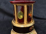 an image of a red and gold clock sitting on top of a black table