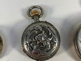 three different types of pocket watches sitting on a white surface